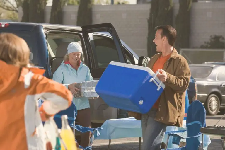 man loading cooler into truck, woman bringing foil items and a grocery buggy